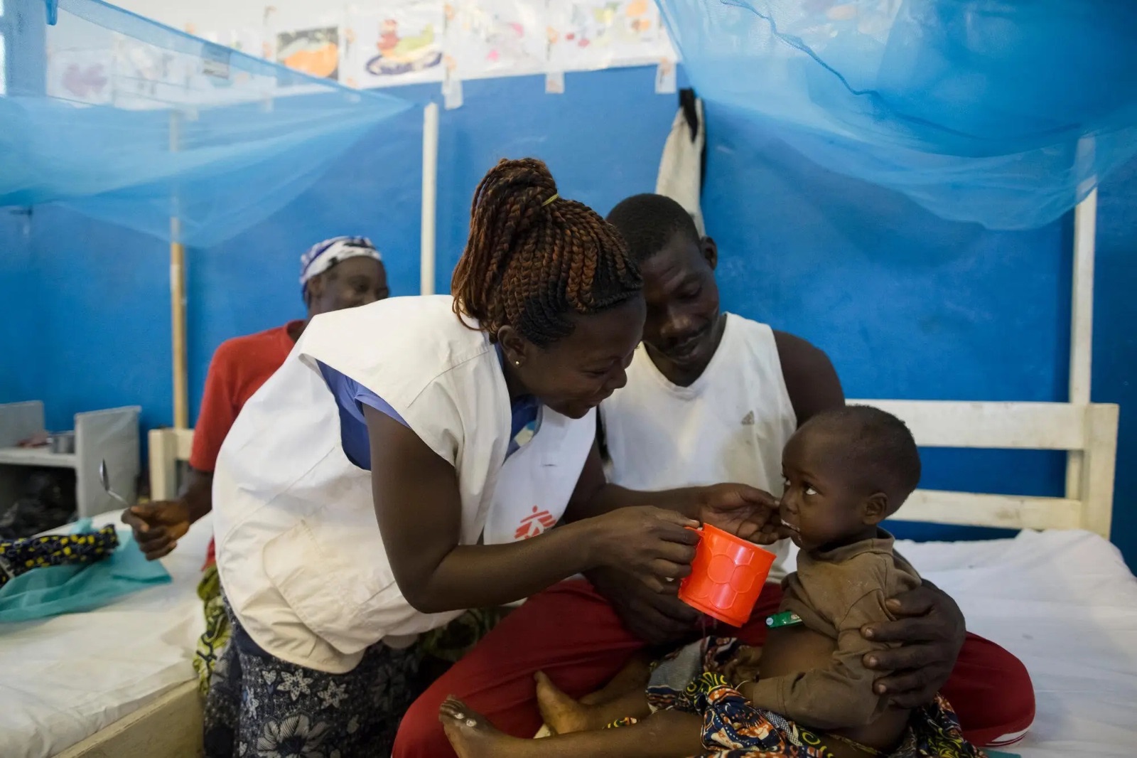 A Médecins Sans Frontières worker feeding a young child in a care ward