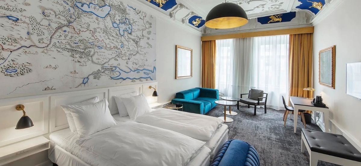 A Jørgensens Hotel guest room with a historic map of Horsens on the wall and a wall-mounted smart TV