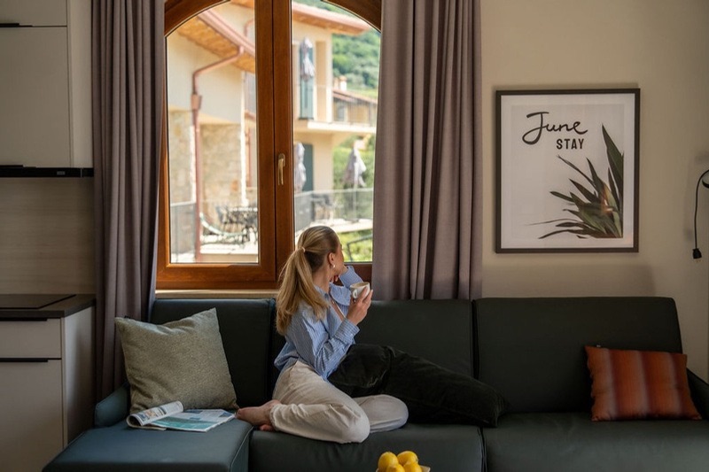A guest relaxing with a coffee in a Primestar June Stay apartment overlooking Lake Garda