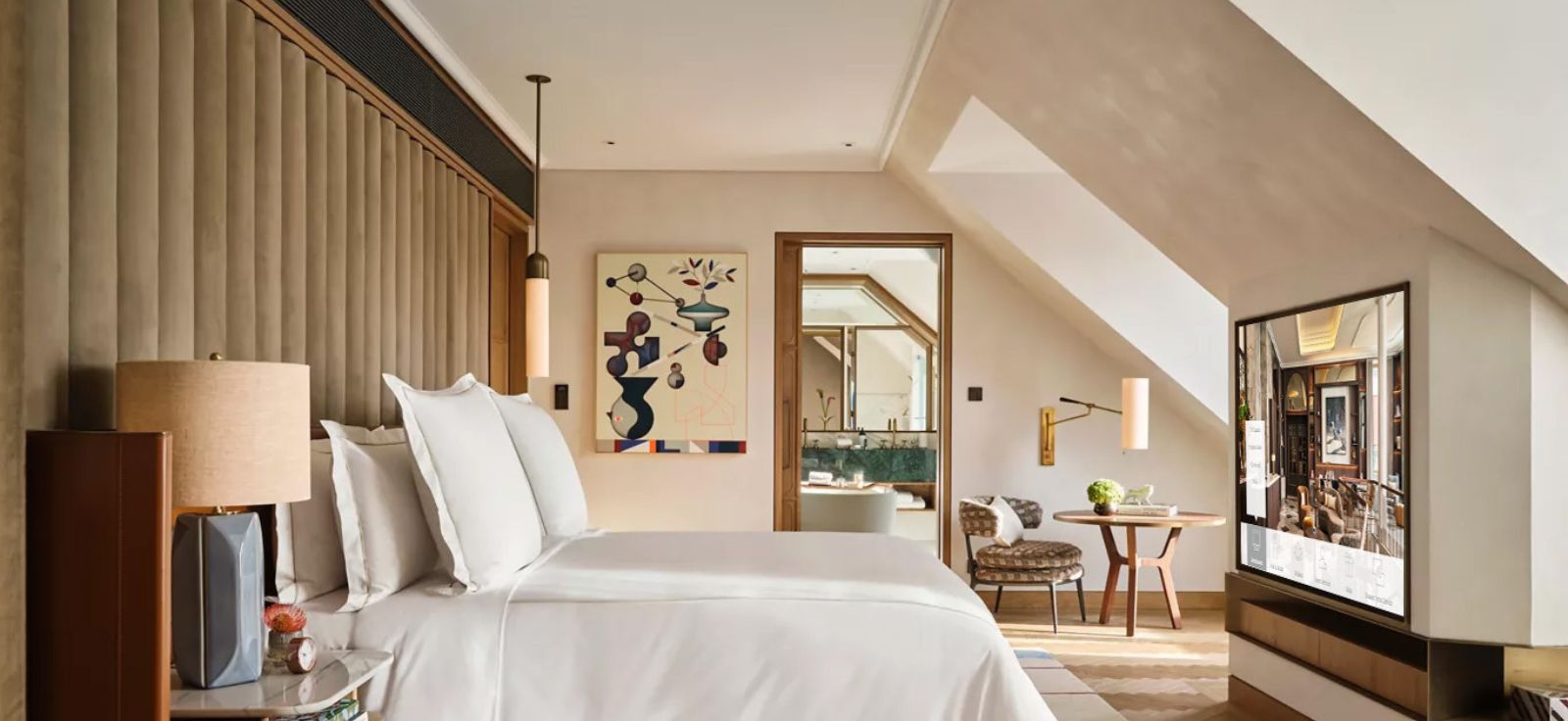 A Rosewood Munich guest room with a wall-mounted TV showing curated hotel content