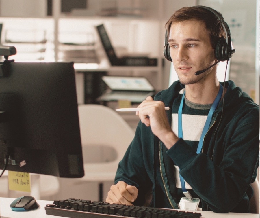 A support specialist with a headset working at a help desk, ready to respond